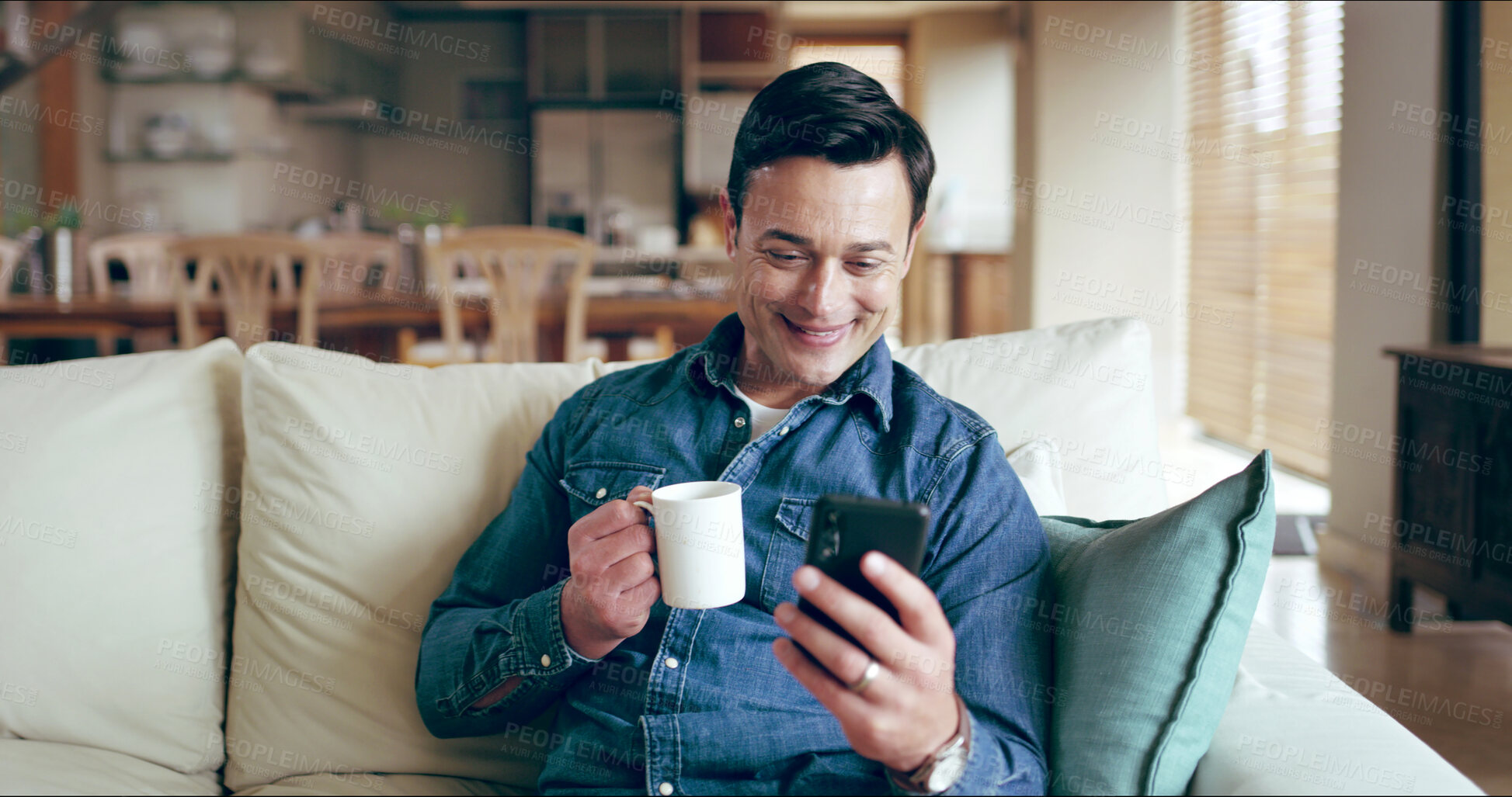 Buy stock photo Man, smartphone and smile with coffee on sofa for texting, chat or reading funny post on mobile app in home. Person, phone and relax with tea cup, drink and happy for contact on social media in house