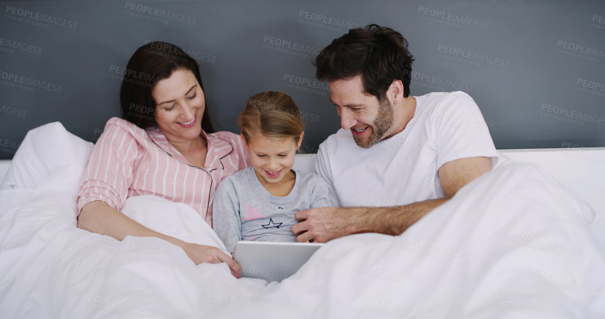 Buy stock photo Relax, tablet and child with parents in bed in home for watching show, film or video online. Happy, rest and girl kid with mom and dad for streaming movie with digital technology in bedroom in house.