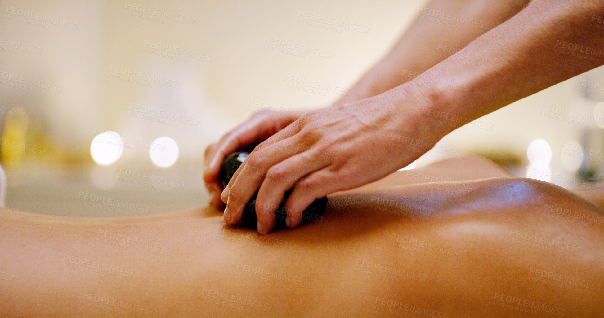 Buy stock photo Hands, person and massage with hot rock at spa of muscle recovery, natural detox and body treatment. People, masseuse and warm stones for holistic healing, stress relief and wellness at luxury resort