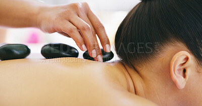 Buy stock photo Person, hands or masseuse with hot stones on back at spa for relaxation, release tension or stress relief. Closeup, massage and client with heated rocks for physical therapy, salon treatment or detox