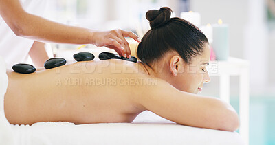 Buy stock photo Woman, hands and massage with hot stones on back at spa for relaxation, release tension or stress relief. Female person, masseuse and client with heated rocks for therapy, treatment or detox