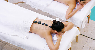 Buy stock photo Women, relax and above with hot stones at spa for massage, stress relief or release tension. Top view, female people or clients lying on bed with heat rocks for detox or physical therapy at salon