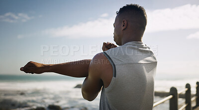 Buy stock photo Seaside, man and arm stretching for fitness with warm up for exercise, training and workout. Male person, muscles and flexibility at beach as routine for health, self care and wellbeing in Brazil