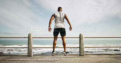 Buy stock photo Fitness, beach and back of man with workout, running or marathon training outdoor for speed. Jump, warm up and male athlete with exercise for cardio on promenade by ocean or sea for wellness.