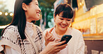 Phone, laughing and girl friends in city reading online blog for celebrity gossip together. Happy, night out and Japanese women with cellphone scroll on social media, internet or mobile app in town.