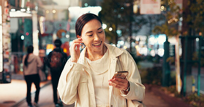 Buy stock photo Happy, asian woman or night with earphones for music, listening or radio podcast in city. Japan, female person or tourist with smile on mobile smartphone for sound or audio streaming in an urban town