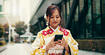 Asian woman, kimono and typing with phone in city for communication, travel or chatting. Japan, female person or tourist with mobile smartphone for travel, online texting or app in an urban town