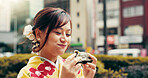 City, smile and girl in kimono eating onigiri on street with happy face, morning commute and breakfast snack. Urban, rice ball and woman with traditional Japanese clothes, food and culture for travel