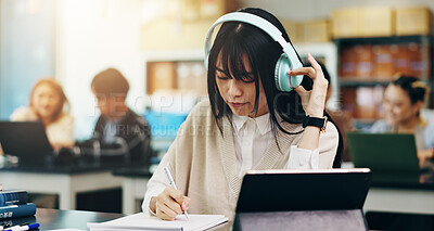 Buy stock photo Headphones, tablet and woman writing at university with notes for literature assignment in class. Education, pen and Japanese student with digital tech studying for college exam, test or project.