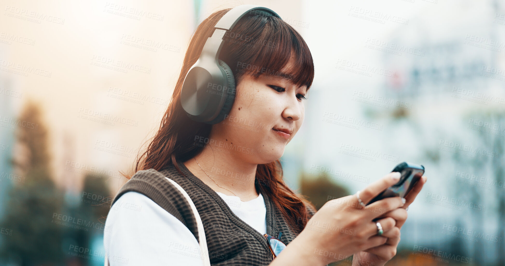 Buy stock photo Woman, headphones and student travel with phone in nature, streaming song and online for message. Female person, university campus and hearing sound on journey in Japan, typing and college email