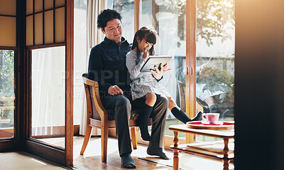 Buy stock photo Education, reading or tablet with father and daughter on chair in home for child development or learning. Japanese family, study or tech with single parent man and girl in apartment for search