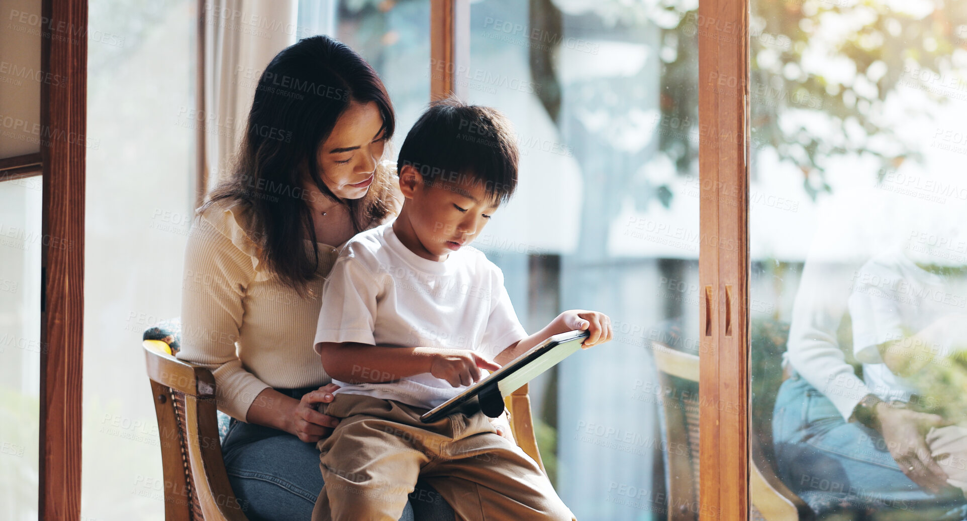 Buy stock photo Education, reading or tablet with mother and son on chair in home for child development or learning. Japanese family, study or technology with single parent woman and boy in apartment for search