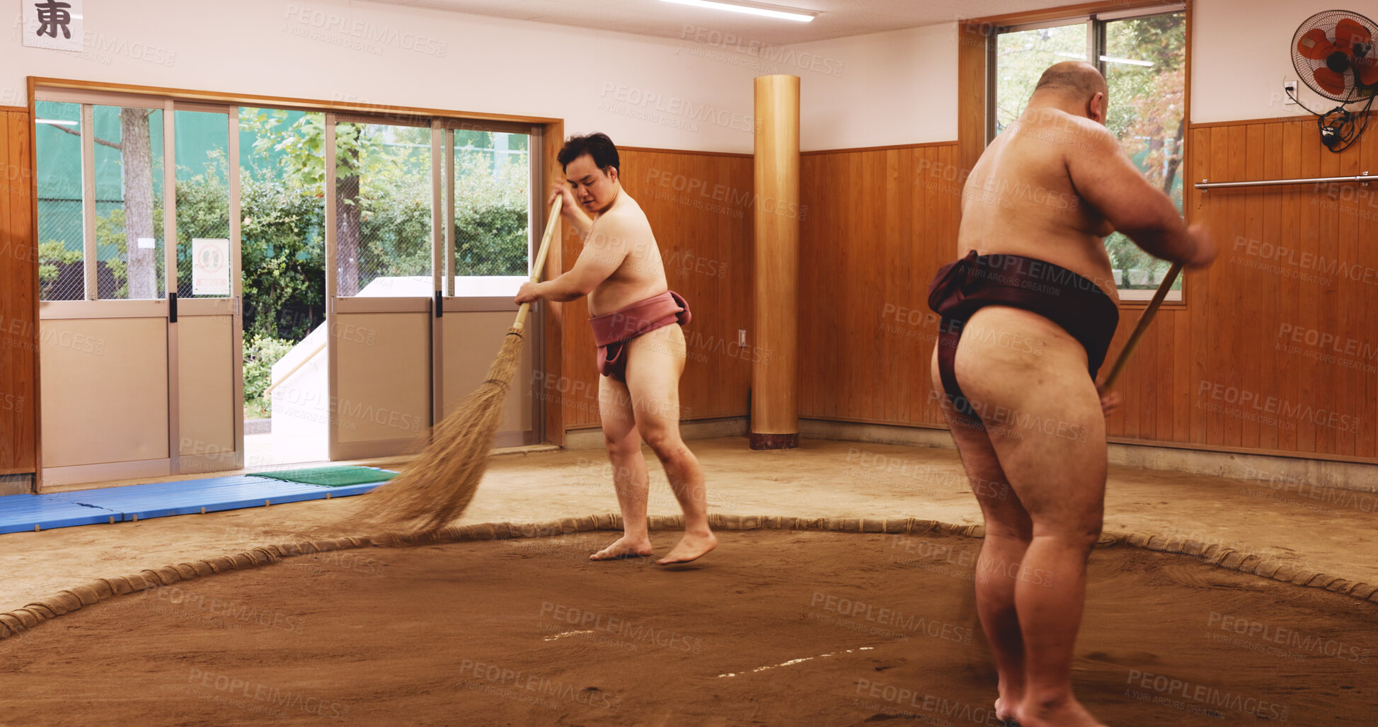 Buy stock photo Ceremony, broom and dohyo with Sumo wrestler people sweeping sand in mawashi, getting ready for competition. Cleaning, prepare and start with men in Japan for culture, heritage or martial arts