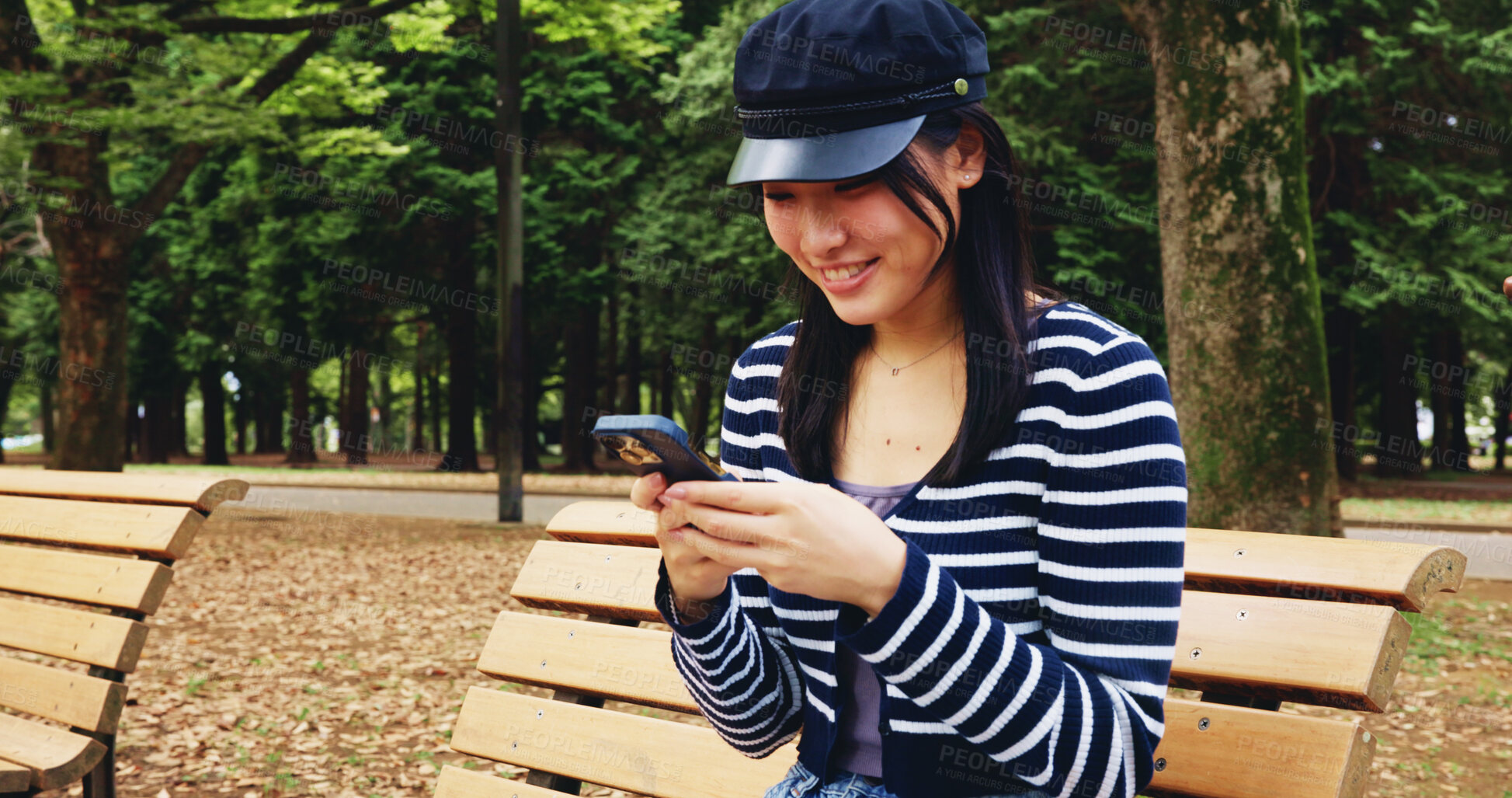 Buy stock photo Bench, phone and smile with woman in park for adventure, sightseeing or travel to explore Japan. App, break and social media with smile of happy tourist person outdoor in nature for vacation