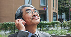 Business, music and thinking with mature man outdoor in city for break from job or work. Headphones, idea and vision with corporate Japanese employee outdoor in urban town for future or planning