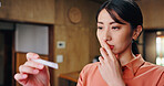 Japanese woman, pregnancy test and surprise baby as worry, fear or anxiety in house for results. Female person, shock and stress as future mother in living room for thinking, planning and family home