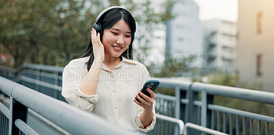 Buy stock photo City, happy woman and headphones for music on mobile, streaming podcast or travel. Phone, outdoor and Japanese girl listening to audio on internet, sound and jazz song on radio app online on bridge