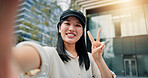 Asian woman, portrait and selfie with peace sign in city for picture, photography or memory. Japan, female person or tourist with smile, emoji or hand gesture for capture or moment in an urban town