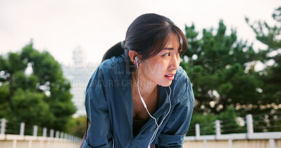 Buy stock photo Tired, woman and fitness with earphones in city from sport exercise, marathon training and listen to music. Athlete, fatigue and break of cardio workout, physical recovery and podcast on Japan bridge