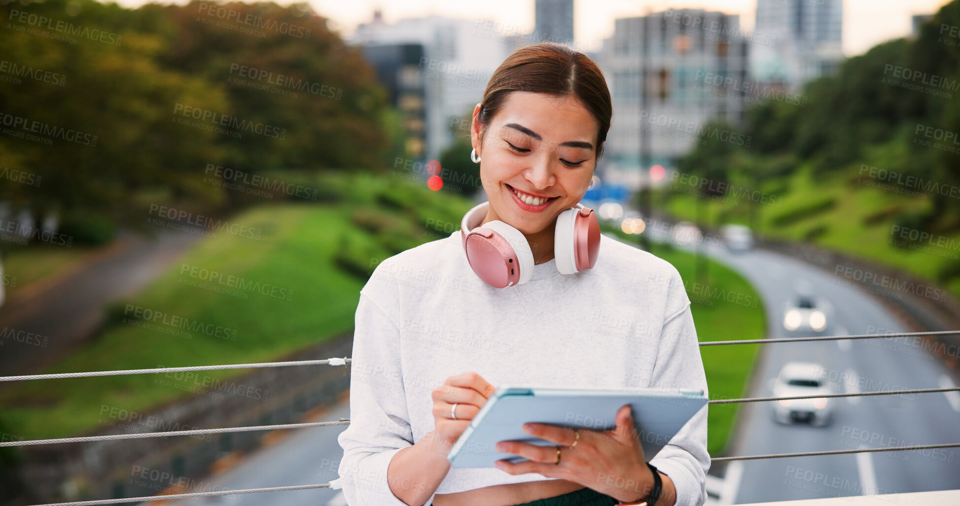 Buy stock photo Smile, woman and writing on tablet in city for graphic design, digital illustration and creative process. Female artist, headphones and drawing for website, editing update and project on Japan bridge