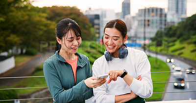 Buy stock photo Fitness, happy friends and women with phone in city for social media, training app or show text. Japanese girls, sports and outdoor with mobile for body health, exercise results or tracking wellness