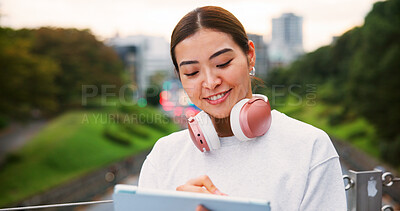 Buy stock photo Japanese woman, smile and tablet in city for copywriting, reading article and publishing process. Female writer, headphones and review blog with newsletter, editing update and project on Japan bridge