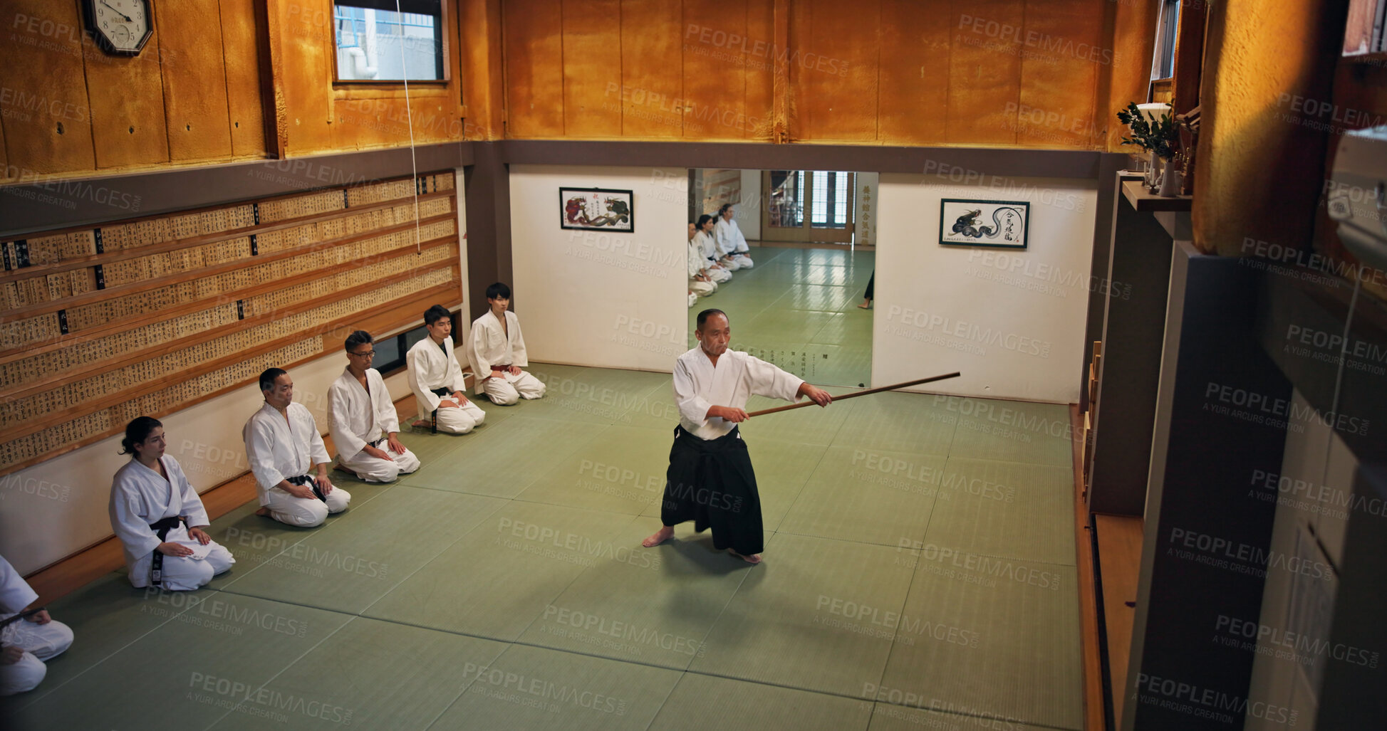 Buy stock photo Dojo, master and demonstration of Aikido training in class with wood sword Japanese martial arts and fight exercise in studio. Learning, sport and bamboo weapon with people and strike practice above