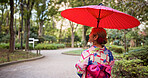 Kimono, umbrella and walking with woman in park to explore green location for sightseeing or tourism. Back, fashion and travel with person outdoor in nature of Japan for culture, holiday or vacation