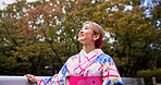 Woman, thinking and walking with bridge, park and travel for journey and natural sustainability. Japanese person, cultural fashion and holiday or vacation with kimono, garden and outdoor to relax