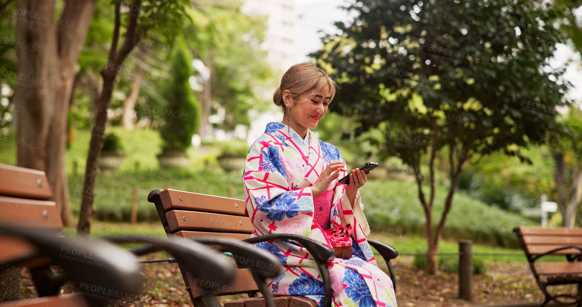 Buy stock photo Smile, park and Japanese woman with phone for social media, text message or reading ebook on internet. Asian girl, mobile and outdoor on bench for relax, chat app and traditional kimono for culture