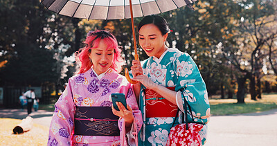 Buy stock photo Phone, umbrella and Japanese women in park with smile, kimono and outdoor adventure together. Nature, culture and happy girl friends with traditional clothes, parasol or mobile app for online chat