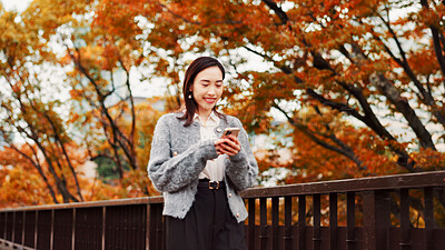 Buy stock photo Typing, smile and woman with phone at park for travel, text or blog on notification app in Japan. Happy, mobile and Asian person outdoor for chat, reading and post on social media profile on internet