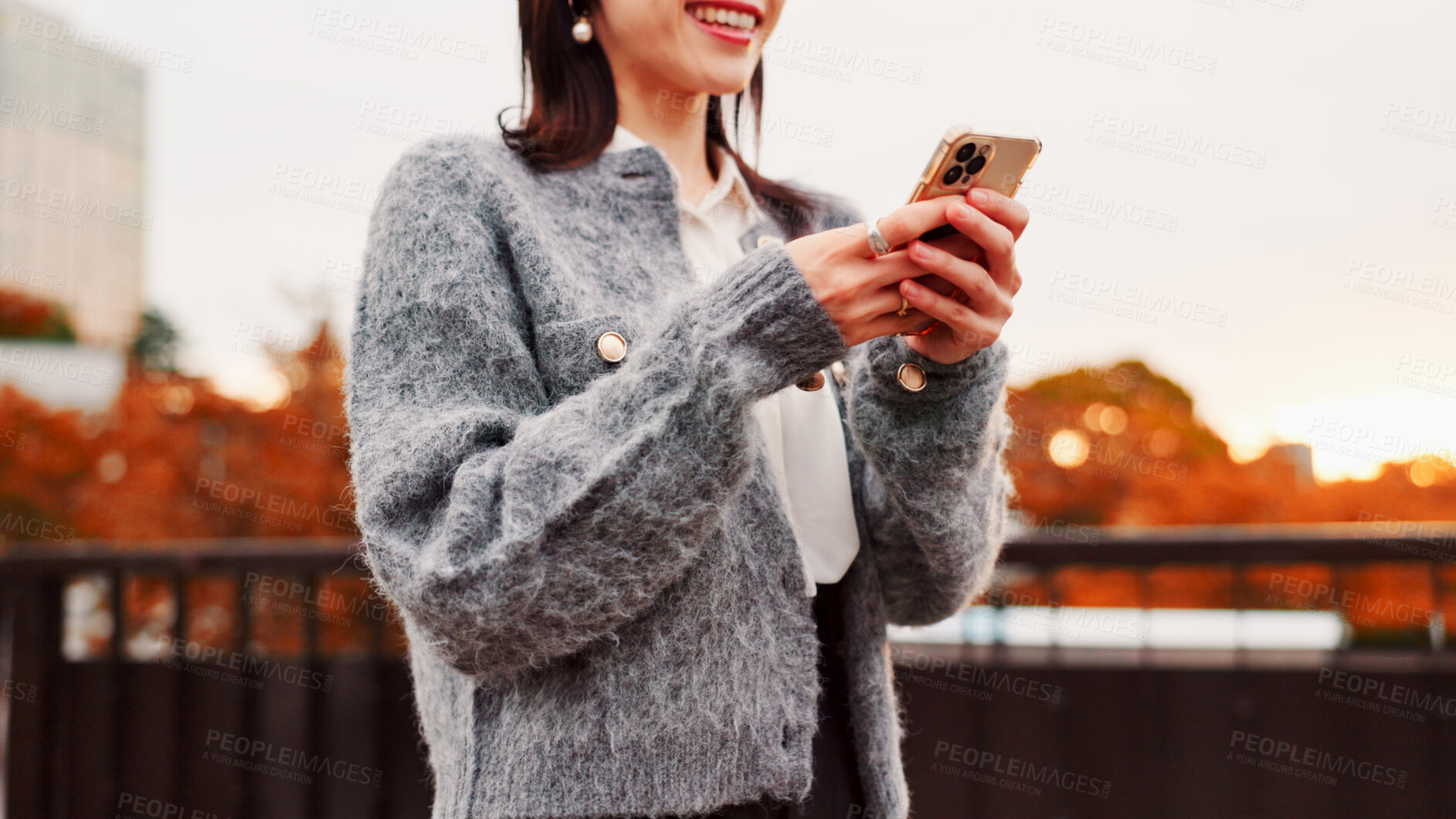 Buy stock photo Hands, phone and happy woman outdoor for travel, text or message on app in Japan. Smile, mobile or female person at park for chat, communication and post on social media profile on internet at sunset