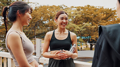 Buy stock photo Personal trainer, fitness and break for women, exercise and routine in morning, outdoor and bonding. Talking, workout and Asian people with bottle of water, bridge and wellness for friends in Japan