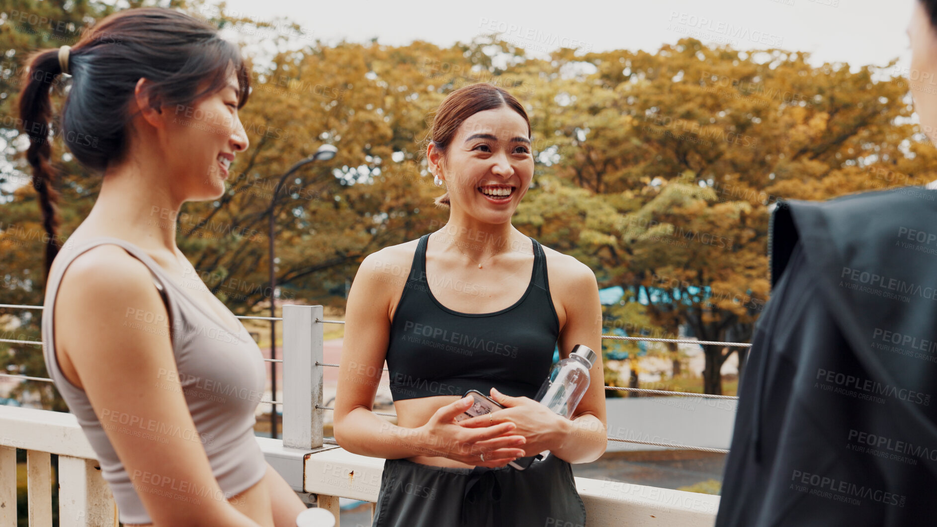 Buy stock photo Personal trainer, fitness and break for women, exercise and routine in morning, outdoor and bonding. Talking, workout and Asian people with bottle of water, bridge and wellness for friends in Japan