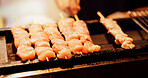 Chicken skewer, hands and Japanese street food on grill, outdoor bbq or meat kebab for dinner. Asian cuisine, festival culture or person cooking traditional yakitori on barbecue at local night market