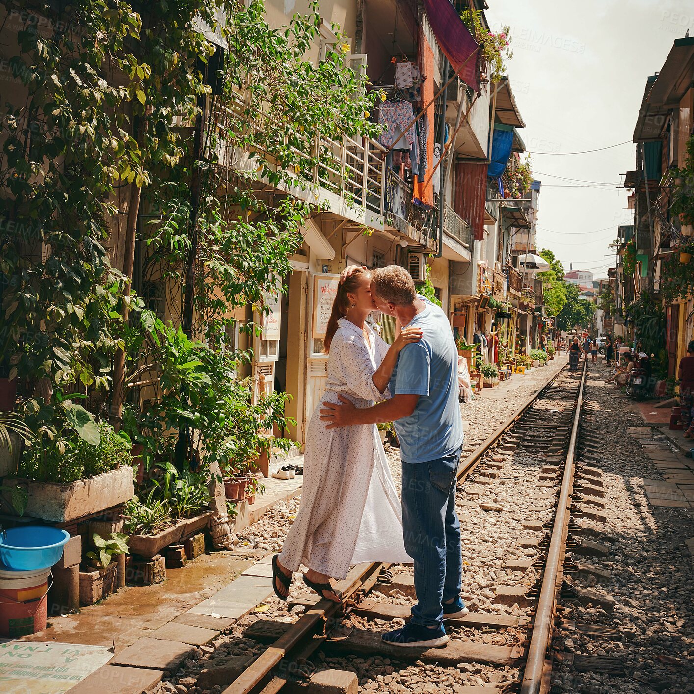 Buy stock photo Happy couple, kiss and railway in city for outdoor, bonding together and honeymoon. Woman, man and travel on train track in town for holiday destination, adventure or vacation with romance in Vietnam