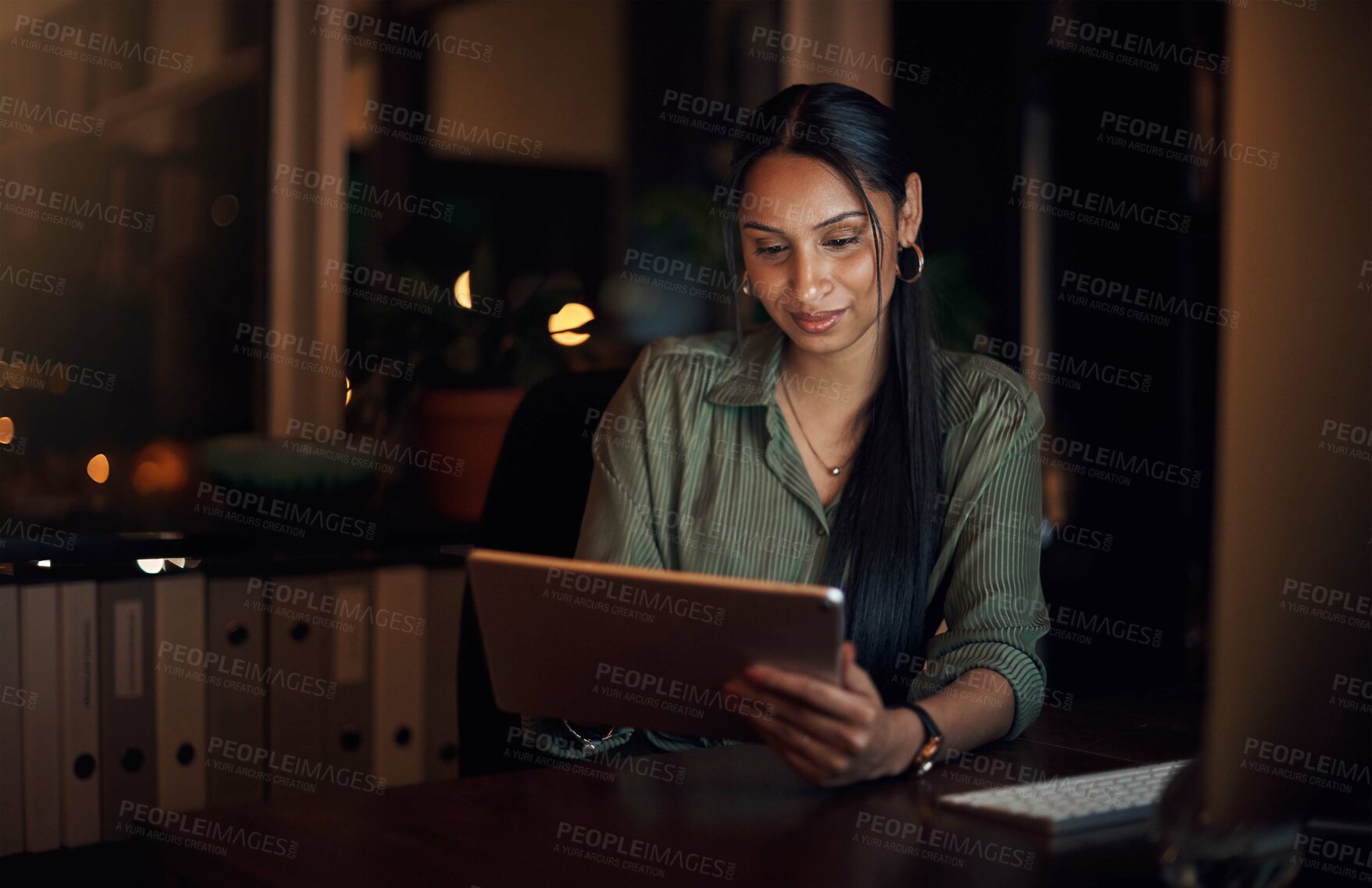 Buy stock photo Shot of a young businesswoman using a digital tablet in an office at night