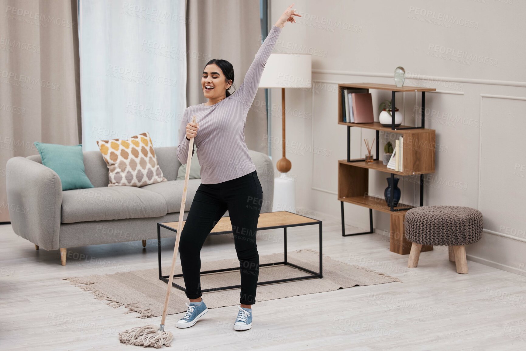 Buy stock photo shot of an attractive young woman having fun while cleaning her home