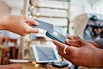 Closeup of unknown mixed race customer using a wireless credit card machine to pay for her coffee. African american barista assisting a woman in a cafe. Contactless paying system during covid pandemic