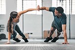 Healthy, fit and active gym partners exercising together and doing pushups with a high five. Boyfriend and girlfriend training and exercising in a health facility as part of their workout routine