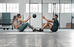 Active, sporty fitness couple or gym partners training together, doing abs exercises by throwing a weighted slam ball. Male trainer and female athlete in motion focused on workout session or class.