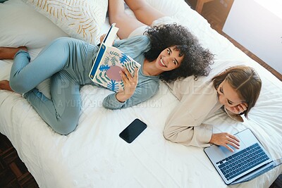 Buy stock photo Laptop, morning and a lesbian couple relax in bed while together in their home on the weekend. Reading, computer and book with happy lgbt woman with her girlfriend in the bedroom from above for love