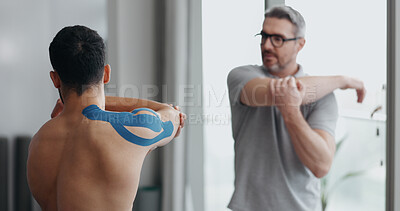 Buy stock photo Physiotherapist, man and stretching with tape for muscle, injury and guide for recovery at clinic. People, help and support with exercise for shoulder pain with progress in rehabilitation at hospital