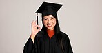 Ok, graduation and smile with portrait of asian woman in studio for success, college degree or award. Achievement, education and university student with person on white background for mockup space