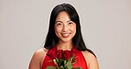 Woman, studio background and portrait with rose for love, care and valentines day celebration in Japan. Japanese person, romance and happy or smile in red dress with flower as anniversary gift