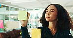 Business woman, writing and schedule planning with glass board for tasks, agenda or reminder at office. Female person, thoughtful employee or creative with sticky notes for project or brainstorming