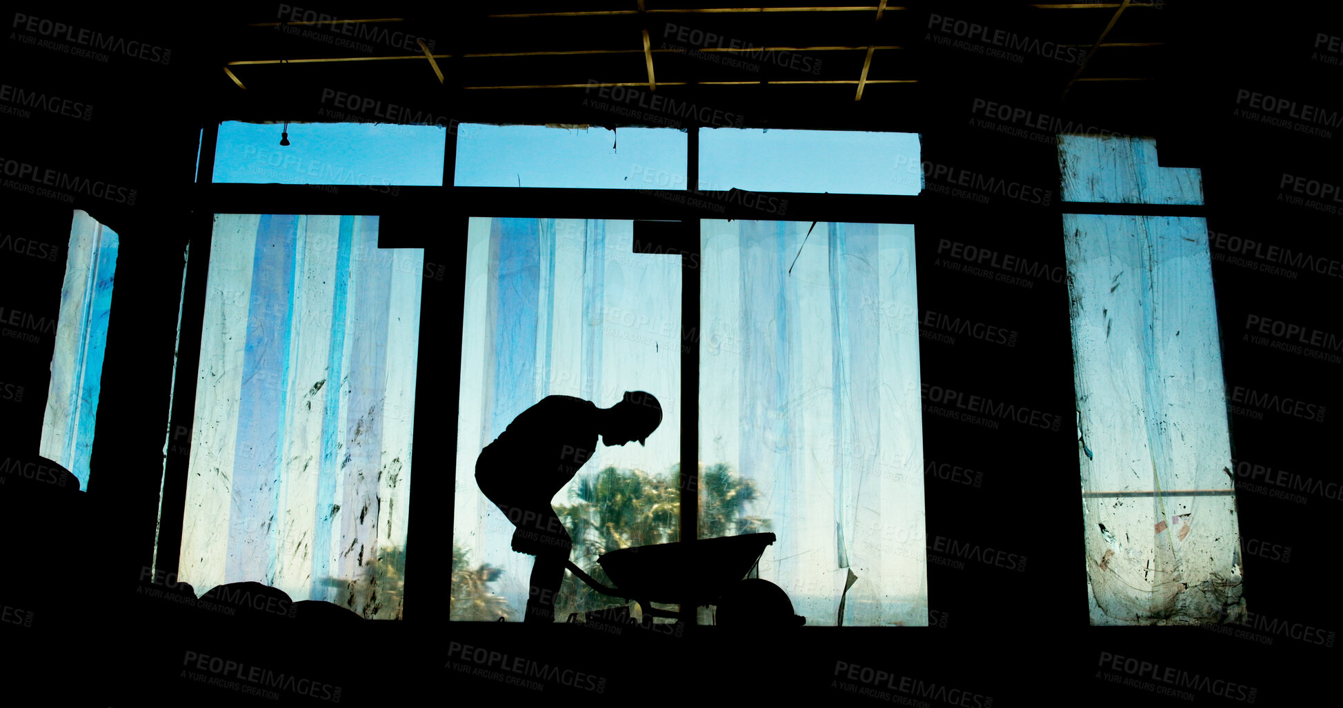 Buy stock photo Construction site, project and worker with wheelbarrow, architecture and silhouette of employee in property. Industry, service and person with helmet for renovation, working and labor for maintenance