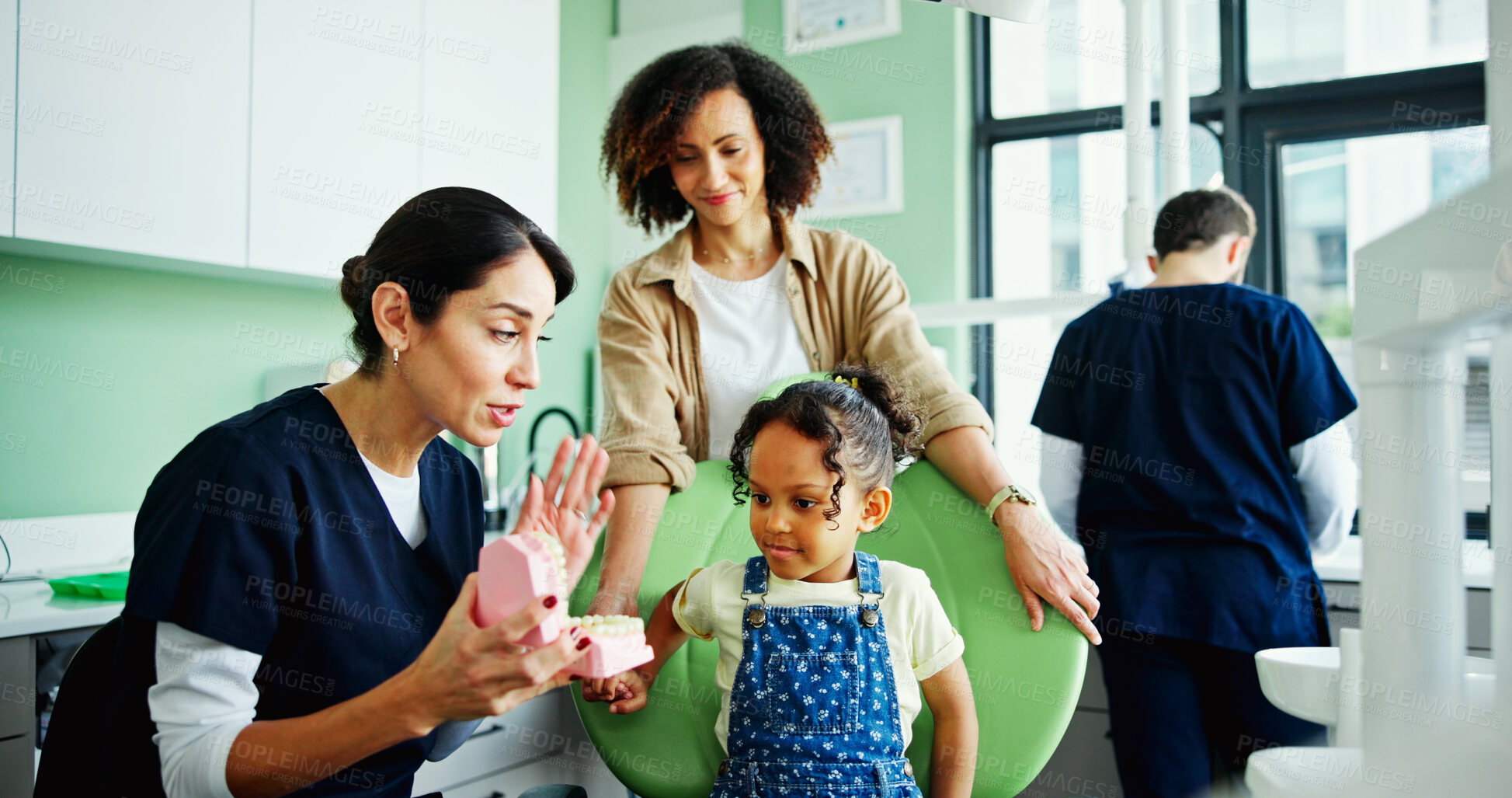 Buy stock photo Dentist, girl and woman with teaching with model, gums and teeth for oral care, info or listening at clinic. Doctor, mother and daughter with mouth, mold and learning for dental wellness at hospital