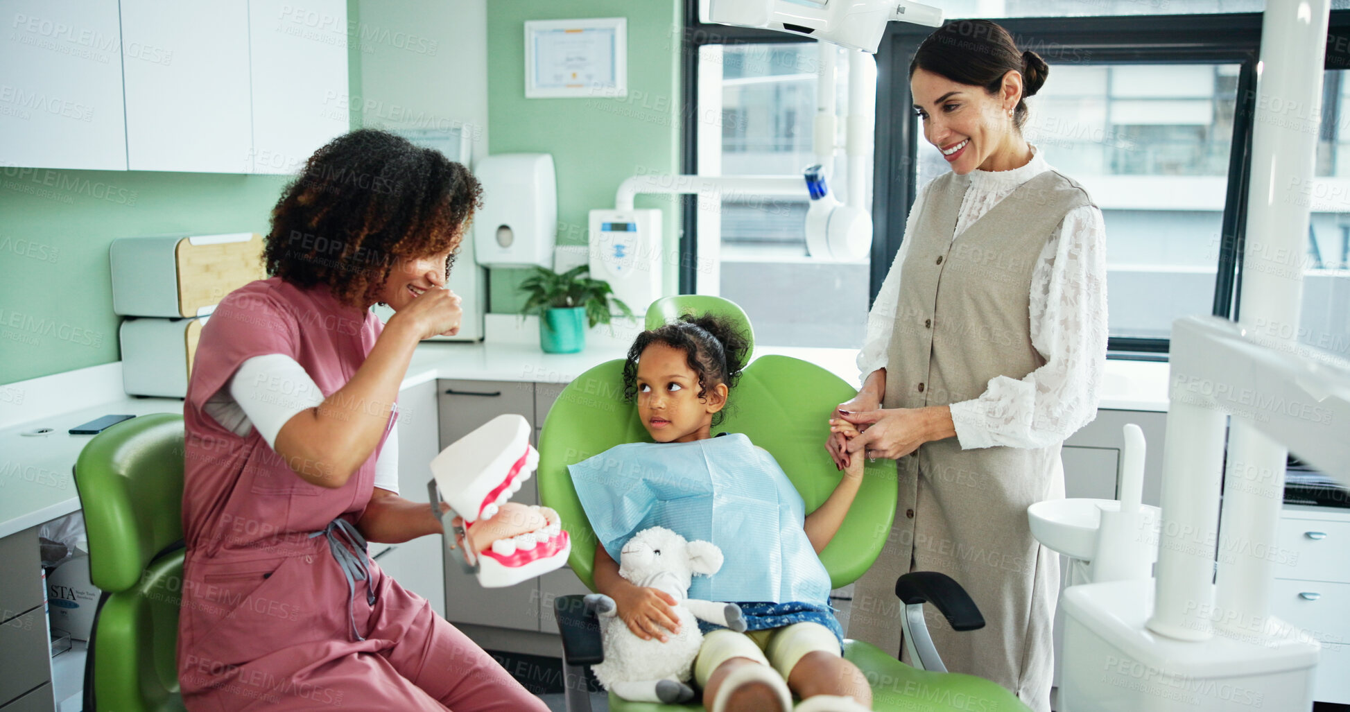 Buy stock photo Dentist, girl and child with teaching, model and info with listening, oral care and advice at clinic. Woman, mother and daughter with presentation, mold and learning for dental wellness at hospital